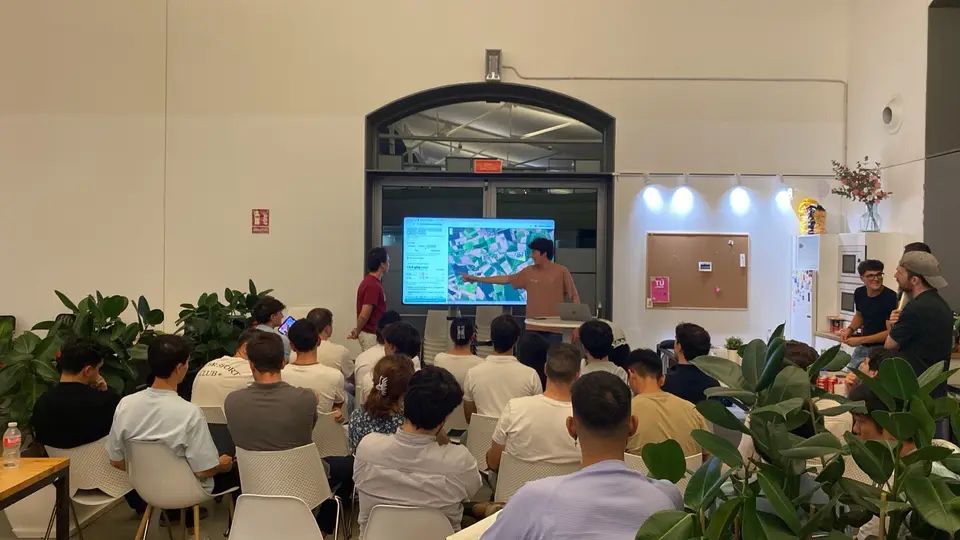 Presenting the demo at the hackathon: a satellite map of real fields on the screen, in front of a full room